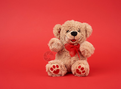 可爱的棕色小泰迪熊玩具坐在红色背景关闭复制空间图片
