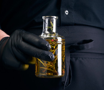 黑衣男子乳胶手套装着一个透明瓶子含橄榄油低密匙关上图片