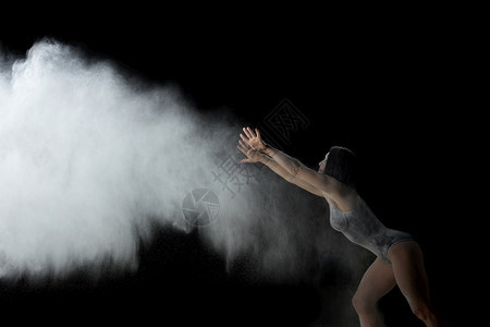 身穿黑色泳装运动服的美女正在黑底面粉的白云中跳舞烟喷射机飞起来背景图片