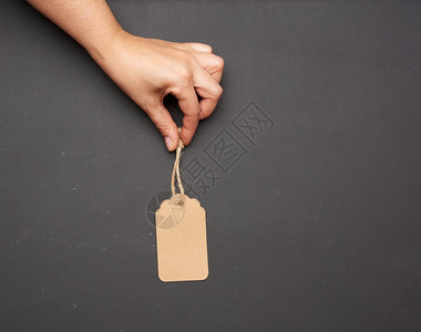 黑色背景复制空间上的绳索手持纸棕色矩形价格标签图片