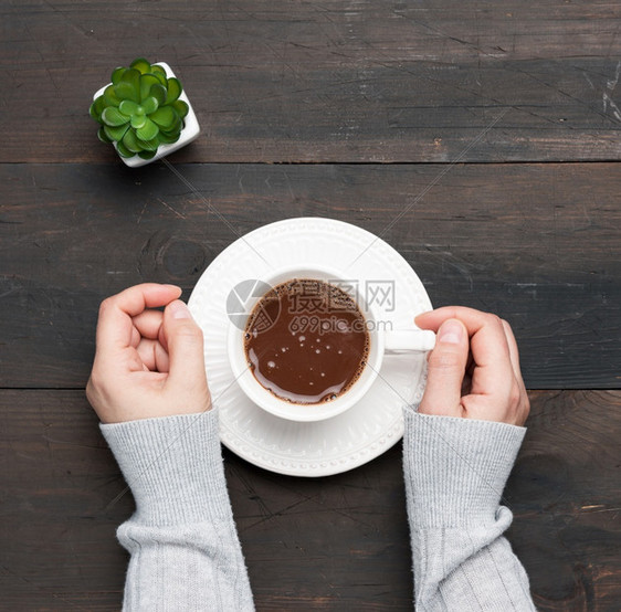 白陶瓷杯咖啡和两只女手放在棕色桌顶图片