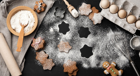 在黑桌和配料上洒满糖粉的烤星形姜饼干最高视图高清图片