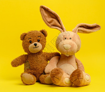棕色泰迪熊和可爱兔子坐在黄色背景上图片