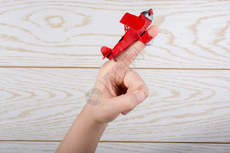 红色玩具飞机放在手指头上图片