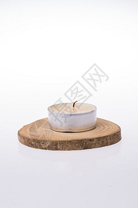 燃烧的蜡烛在白色背景的一块木头上放置的蜡烛背景