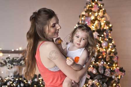 在圣诞节的装饰品上妈把她的女儿抱在怀里背景图片