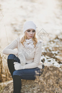 一位女孩坐在9182号公路旁边的一块大石头上冬季肖像背景图片