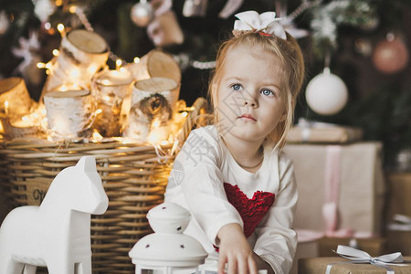 坐在圣诞树下带礼物的小女孩坐在圣诞树724旁边的地板上孩子肖像图片