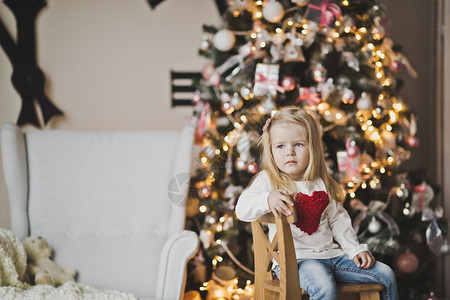 孩子坐在圣诞树729旁边的木椅上图片