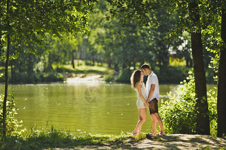 快乐的情侣在湖岸边接吻图片