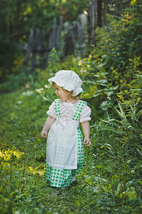 穿着绿色和白衣服的小女孩在花园里走动图片