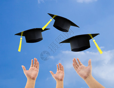 学生们在空中扔毕业帽子庆祝天空背景图片