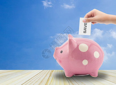 在储蓄和投资概念中将纸和条放在小猪银行的口袋里图片