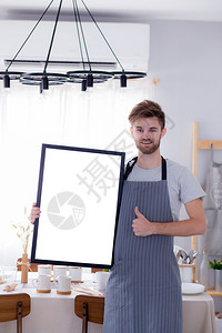 英俊的厨师在餐厅菜单或食谱上展示空的餐桌菜单牌图片