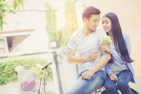 亚洲年轻夫妇在公园骑自行车快乐地骑在公园浪漫的爱情休闲活动关系概念图片