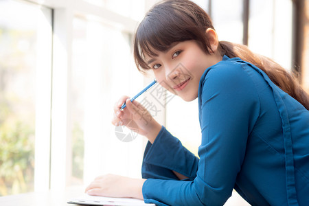 年轻女作家在笔记本或日上微笑着思考想写快乐Asia女孩的生活方式是学女规划工作教育和商业概念图片