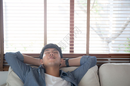 长相英俊的亚洲男子在家中沙发上睡得舒服适男在周末休息和睡觉在度假生活方式和福利概念中睡在沙发上疲倦和懒惰图片