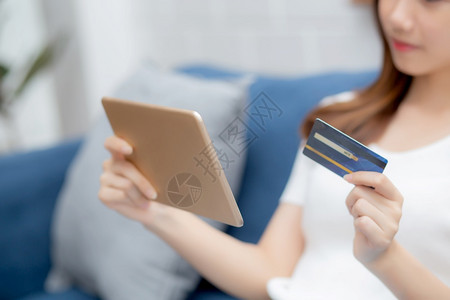 年轻的青女微笑着在网上持有信用卡在网上持有带平板电脑购买和付款的信用卡女孩使借记卡购买或金融交易生活方式和电子商务概念图片