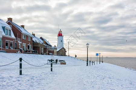 荷兰冬季乌尔克渔村的灯塔有雪和风景图片