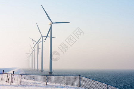 荷兰海近风力涡轮机在冬季烟雾中消失在Haar霜冻覆盖的围栏前图片