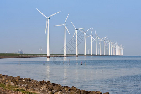 沿海岸线的荷兰风车在平静的海中照耀图片