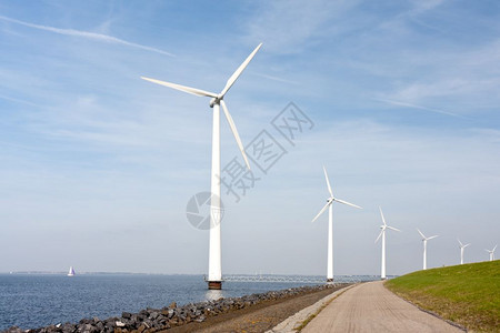 风力涡轮机沿荷兰海堤坝站立图片