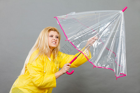 夏雨秋天的首饰思想概念有严肃面部表情的妇女打开清晰透明的伞与风作斗争图片