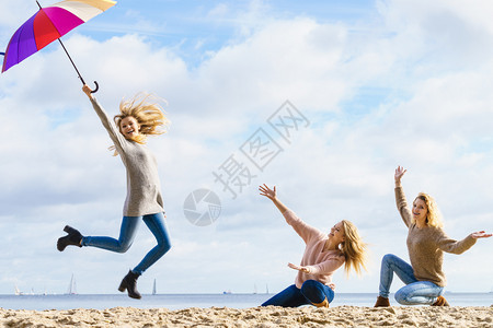 三个充满欢乐的女人带着多姿彩的雨伞到处跳女朋友在户外玩得开心图片