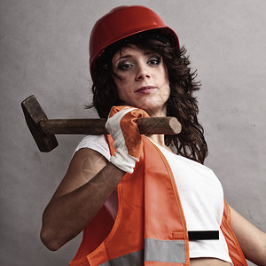 男女平等和权主义戴安全头盔的穿橙色背心感女孩拿着锤子工具有吸引力的妇女从事建筑工人作背景