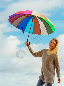 幸福享受秋天的气感受伟大的概念女人在阴云的蓝色天空上拿着多彩的伞快乐女人拿着伞图片