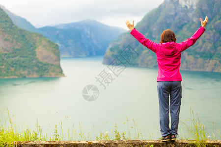 旅行概念自由游妇女快乐享受手举起来望着挪威的fjords山在挪威的Norwegian山码头举起手来的妇女图片