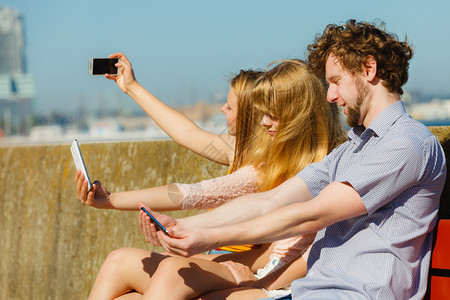 朋友用智能手机拍自照片年轻女和男在户外玩得开心暑假放松图片