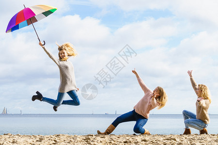三个充满欢乐的女人带着多姿彩的雨伞到处跳女朋友在户外玩得开心图片