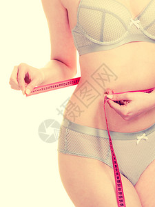 穿内衣的瘦女孩用测量胶带腰部女身体的一部分饮食减瘦体重的时间到了穿内衣的妇女用测量胶带腰部图片