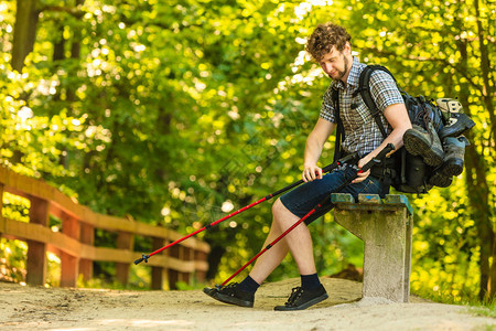 旅游冒险享受暑假青年旅游男子徒步行者背着木棍坐在林道的长凳上北欧高清图片素材