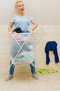 浴室里拿着一大筐脏衣服的女人洗衣店概念家务女人提着一大筐脏衣服图片