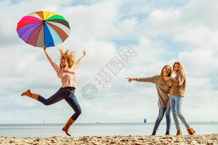 三个充满欢乐的女人带着多姿彩的雨伞到处跳女朋友在户外玩得开心图片