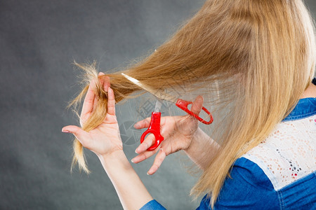 一身金发女人剪了长的直发一手红色剪刀制造现代发型一双金女人剪了头背景图片