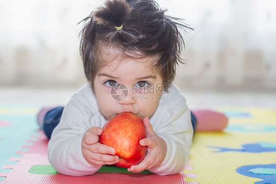 可爱小女婴的肖像她抱着吃一个大红苹果图片