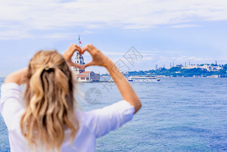 美丽的女旅行者在土耳其伊斯坦布尔的一个受欢迎目地MaidensTower的风景上手牵造心形图片