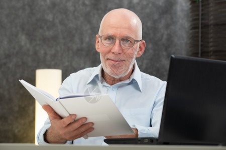 有白头发和眼镜的老人阅读一本书图片