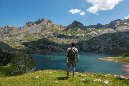 一个男人徒步旅行者休息和看着湖在比利牛斯山图片