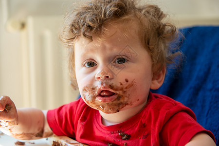 婴儿正在吃巧克力蛋糕高清图片
