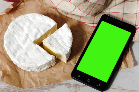 传统的法式奶酪和智能手机的绿色屏幕图片