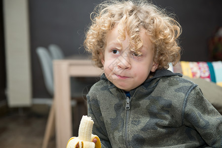 一个金发小男孩吃香蕉图片