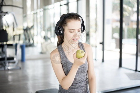 在健身房的漂亮年轻运动女子绿色苹果健康生活方式图片