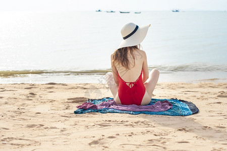 穿红泳衣的美女背面坐在沙滩上图片
