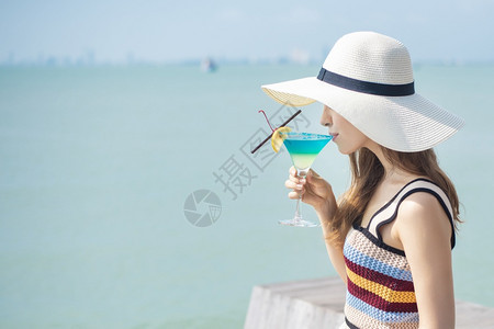 美丽的女人正在海滩喝冰水夏天在海滩喝水夏天的概念图片