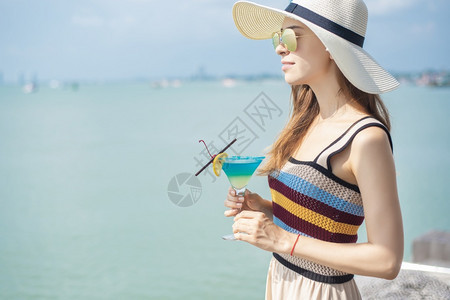 美丽的女人正在海滩喝冰水夏天在海滩喝水夏天的概念图片