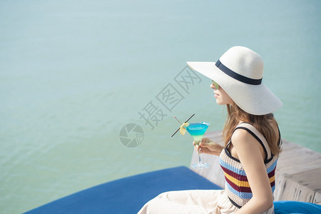 美丽的女人正在海滩喝冰水夏天在海滩喝水夏天的概念图片